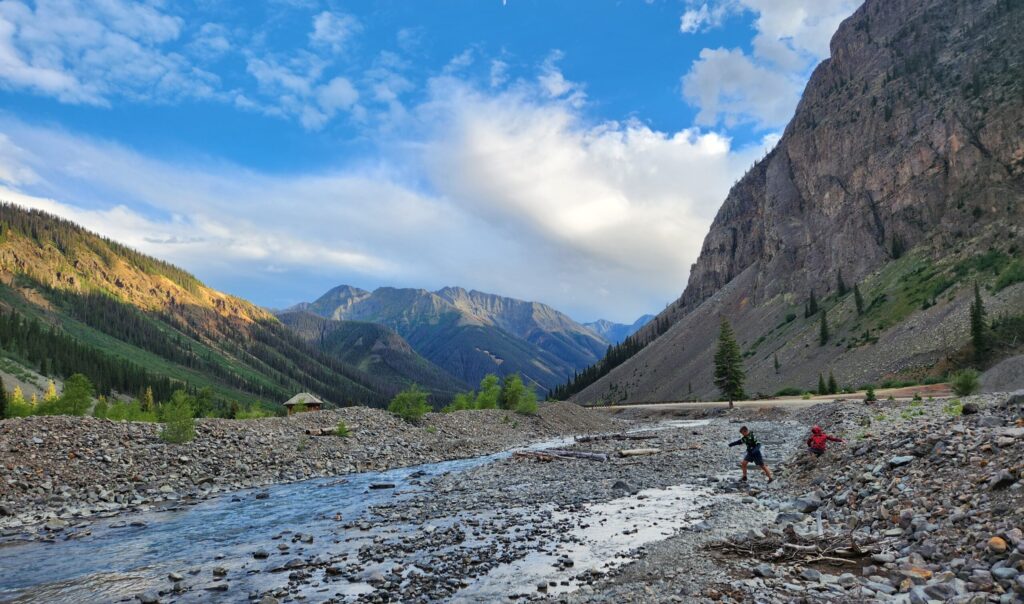 Children playing in water at the base of a mountain.